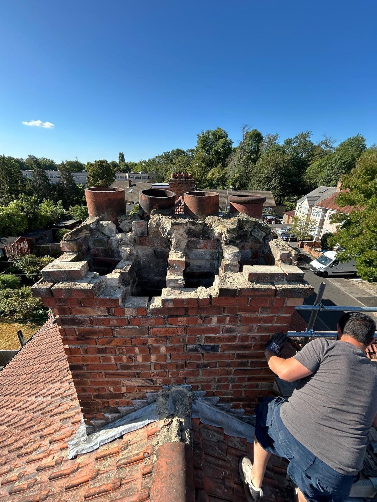 Tradesman repointing the brickwork of a chimney stack during a roof restoration